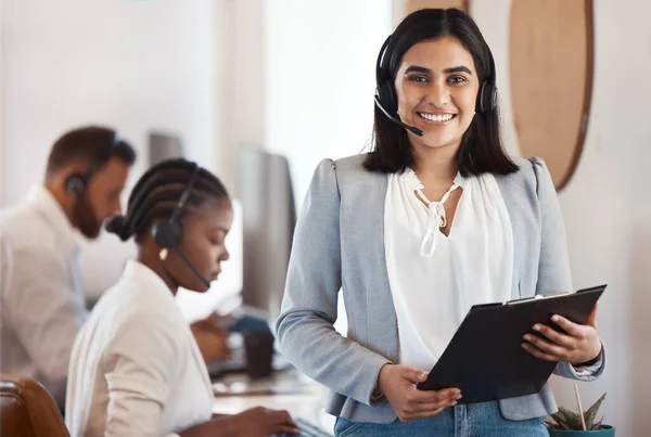 I see to it that my team are always on top. Portrait of a young call centre agent holding a folder in an office with her colleagues in the background