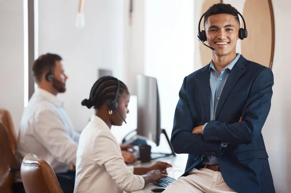 My team are trained to handle any inquiry. Portrait of a young call centre agent working in an office with his colleagues in the background