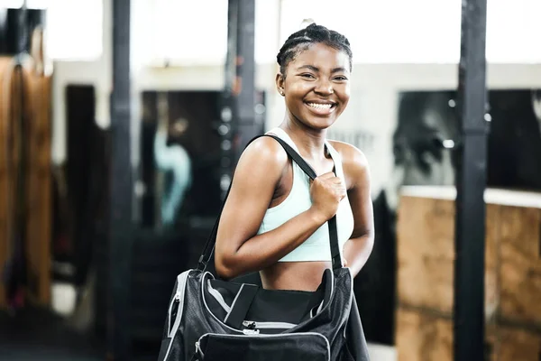 The mornings are made for the gym. an attractive young woman standing alone in the gym and holding a sports bag