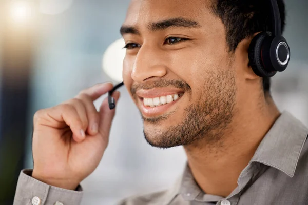 Here to help you fight the blues. a young male call center agent on a call with a customer at his desk