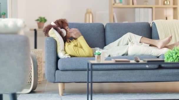 Genç Siyahi Kadın Kulaklık Takıyor Evde Bir Kanepede Dinlenirken Telefonda — Stok video