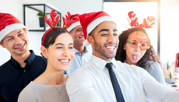 Some Christmas time fun. a group of businesspeople taking a selfie at work