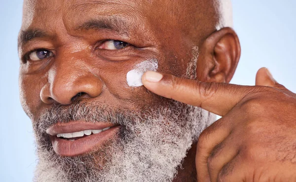 Self-care doesnt age. Studio portrait of a mature man applying moisturiser to his face against a blue background