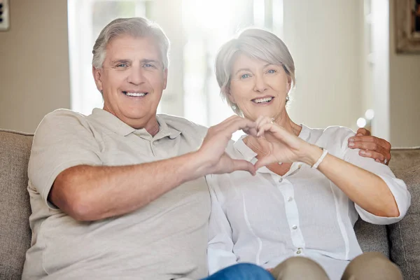 Wasnt love at first sight. It took five minutes. a mature couple making a heart sign with their hands at home