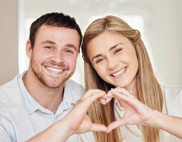 They are Gods gift to you. a young couple making a heart sign with their hands at home