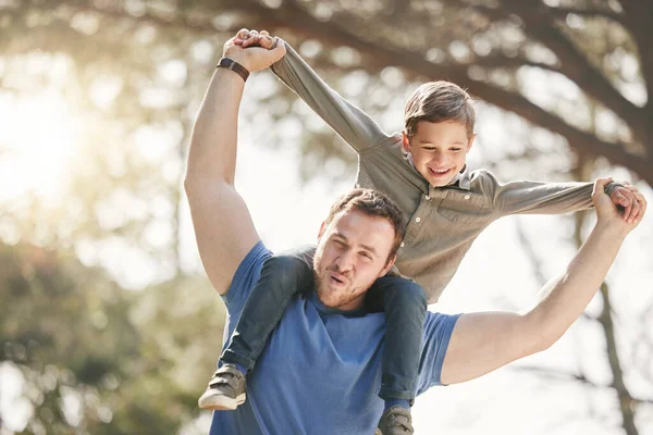 Happy caucasian father and son having fun and playing together outside. Carefree man carrying excited son on his shoulders while bonding in at the park. Single dad enjoying quality time with kid.