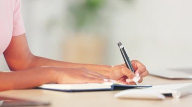 Journalist taking notes and planning their next story while studying at a desk in an office alone at work. Student doing an exam and writing in a book. One person brainstorming and making plans.