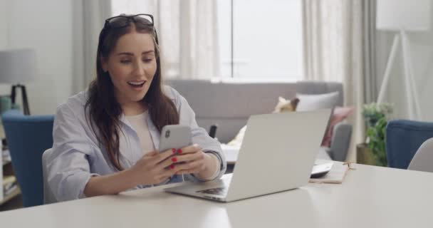 Izgalmas Szabadúszó Üzenetet Olvas Telefonon Gépel Laptopon Miközben Otthonról Dolgozik — Stock videók