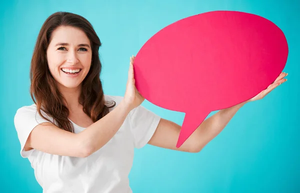 Have your say. Studio portrait of an attractive young woman holding up a blank speech bubble against a blue background