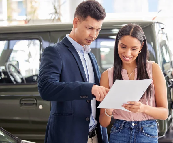 I think this is a great deal. a car salesman and a customer looking at paperwork