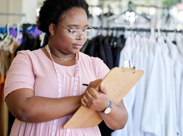 Filling out the order form. an attractive young seamstress writing notes while working in her boutique