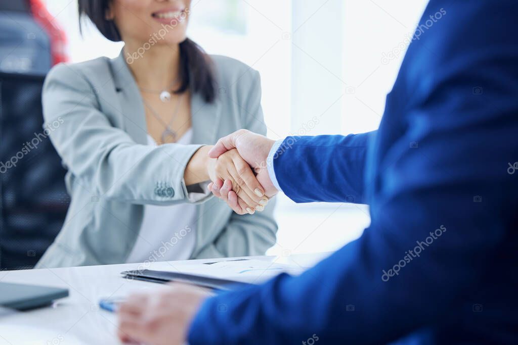 Lets get you to your car. an unrecognizable young woman and a male car salesman shaking hands in his office