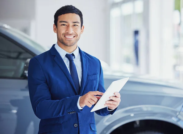 Another sale on the books. Cropped portrait of a handsome young male car salesman working on the showroom floor