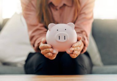 A budget is telling your money where to go. a unrecognizable female holding a piggy bank at home