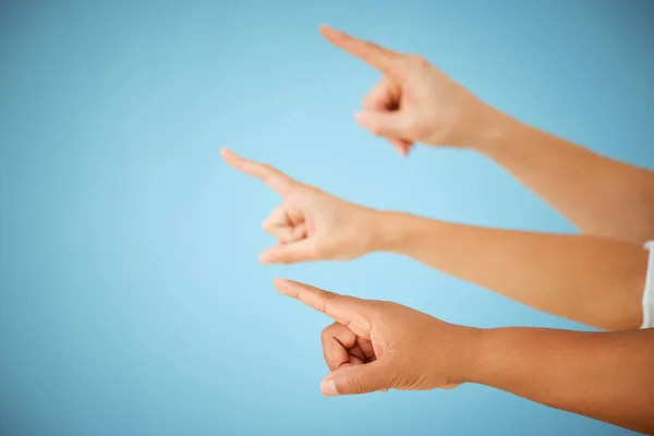 Get all the way out of here. an unrecognizable group of people pointing in the same direction against a blue background