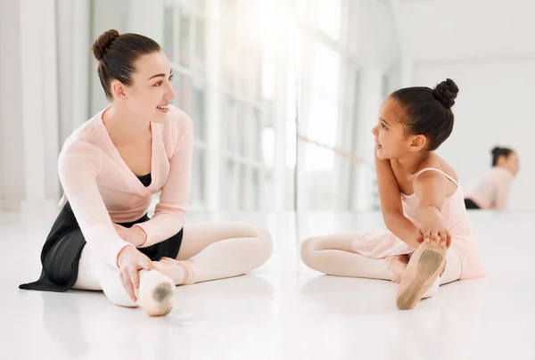 Never underestimate the power of a good teacher. a ballet teacher and student taking a break and talking on the floor of a dance studio