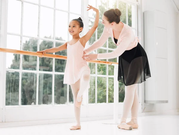 Its all in the posture. a little girl practicing ballet with her teacher in a dance studio