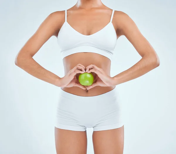 Eating better to reduce irritable bowel syndrome. an unrecognisable woman standing alone in the studio and posing with an apple