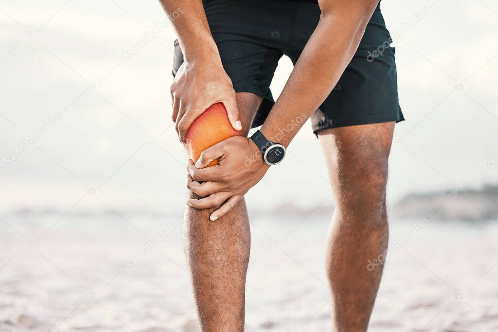 The time to get fit is running out. an unrecognizable male athlete holding his knee in pain while exercising on the beach