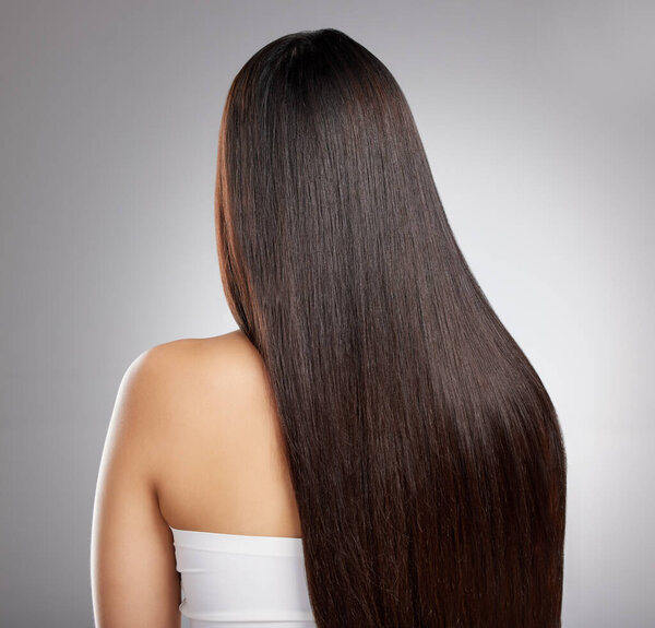 Get yourself into a good haircare routine. Rearview shot of a young woman with long silky hair posing against a grey background