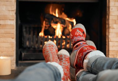 Şöminenin etrafında sıcak tutuyor. Yılbaşı çorabı giymiş bir çiftin evde şöminenin önünde dinlenirken çekilmiş yakın plan fotoğrafları.