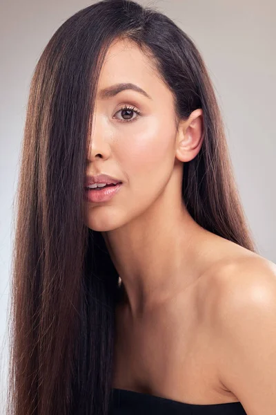 Invest in the right products for your hair. an attractive young woman posing alone in the studio with her hair covering half of her face