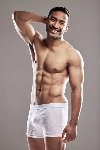 Hes got the ladies swooning. Studio portrait of a muscular young man posing against a grey background