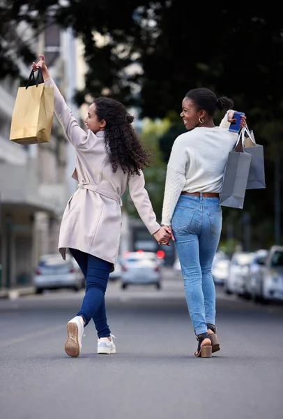 Making our way downtown. two friends cheerfully walking down the street after spending the day shopping