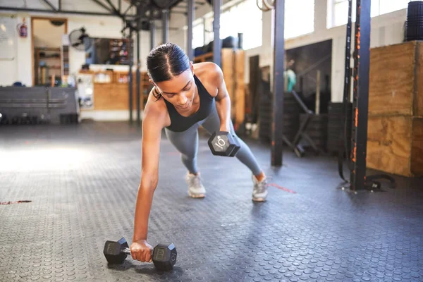 Nothing is too heavy for a strong will. a young woman working out with weights in a gym