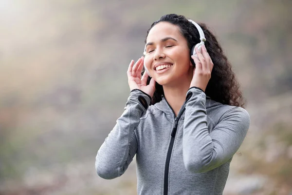 Now this is what I call a good workout playlist. a fit young woman wearing headphones while out in the mountains