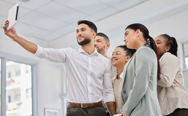 We have some new staff on the team too. Low angle shot of a group of businesspeople taking selfies together on a digital tablet in an office