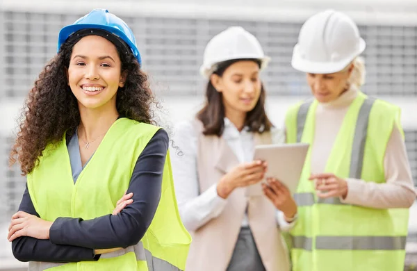 Management is on the job. Cropped portrait of an attractive young female engineer standing with her arms folded with her colleagues in the background on a construction site