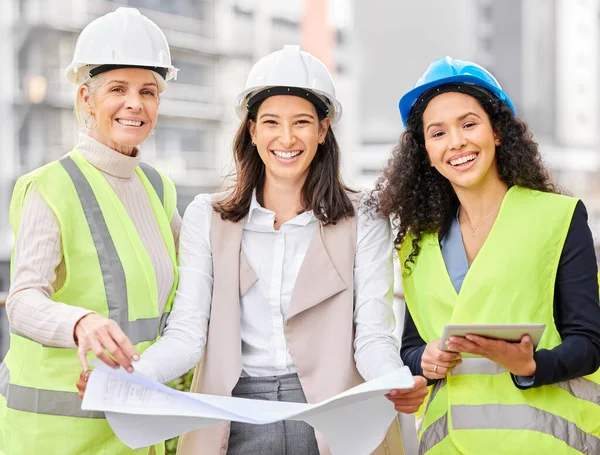 All things go according to plan. Cropped portrait of three attractive female engineers looking at blueprints while standing on a construction site