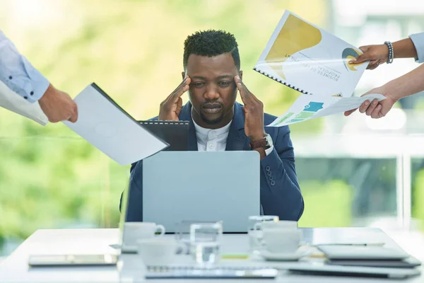 My head is about to explode. a young businessman looking overwhelmed while suffering from a headache in his office