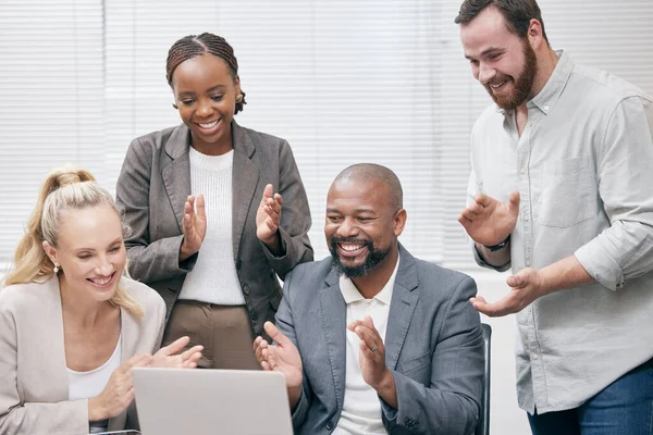 They recognize great work when they see it. a group of white collar businesspeople clapping while gathered around a laptop in the boardroom