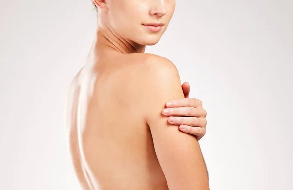 Beauty begins the moment you decide to be healthy. Studio shot of an unrecognizable young woman touching her shoulder while posing against a grey background