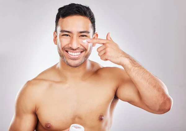 If self-care equates femininity, call me Miss. Studio portrait of a young man applying moisturiser to his face against a grey background