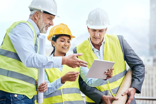 Monitoring workflow directly from their tablet. a group of businesspeople using a digital tablet while working at a construction site