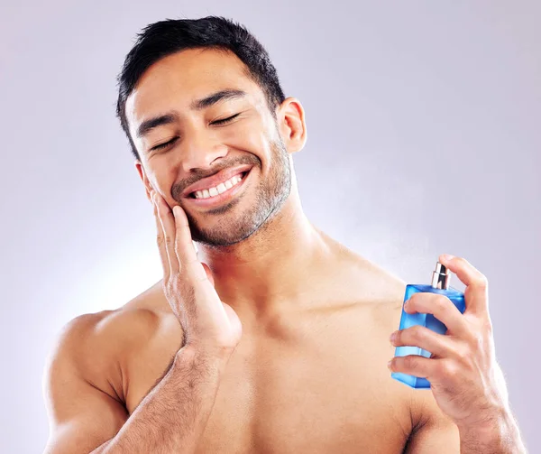 This helps calm the irritation. Studio shot of a handsome young man applying aftershave