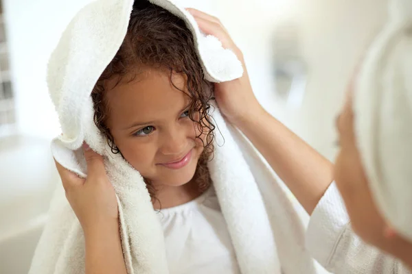 Shower, hygiene and clean daughter bonding with caring, loving and kind mother. Single female parent drying her child with a soft, dry and white towel after a warm bath inside the bathroom at home.