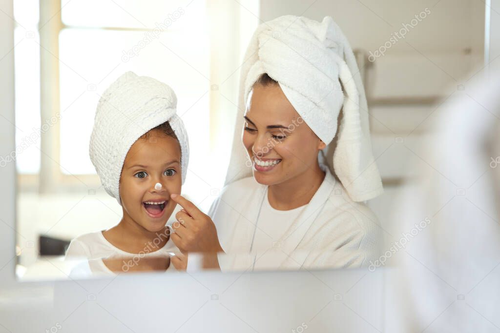 Smiling, joyful and excited little girl in spa with her mother. Mom and daughter self care day, putting on creams and taking care of skin. Parenthood, bonding with child, young female growing up.