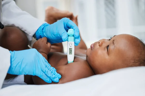 Im going to take good care of you. a little baby having her temperature taken by a doctor with a thermometer