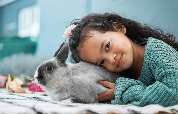 My pet rabbit loves hugs. an adorable little girl bonding with her pet rabbit at home