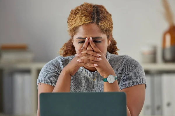 Stressed, worried and upset business woman feeling anxiety and the pressure of deadlines at work. Young female looking unhappy or frustrated while working on a laptop at her desk in the office.