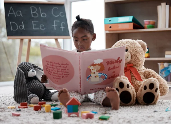 Even my toys like it when I take this book out. an adorable little girl reading a book while sitting at home