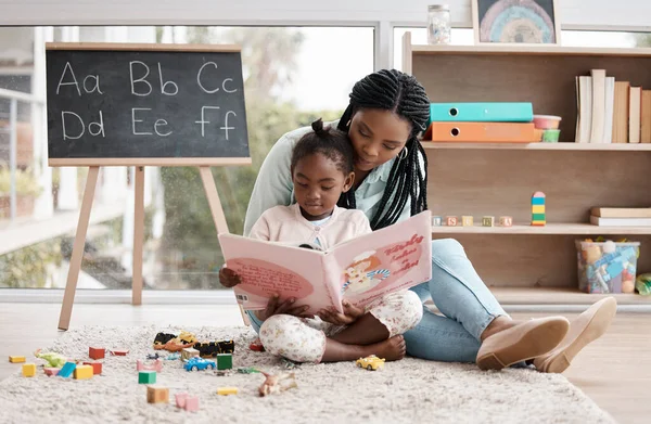 Over a good book is the best way to bond. a woman reading a book to her daughter while sitting at home