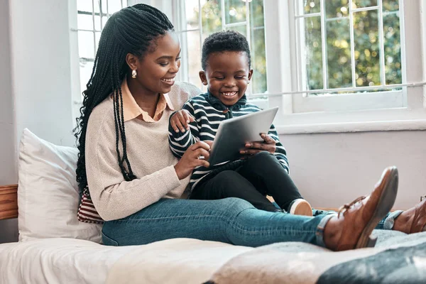 This is one fun-packed app. a little boy and his mother looking at something on a digital tablet while sitting at home