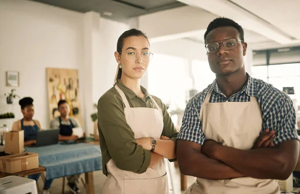 Fashion, design and style with two diverse and professional team members standing arms crossed and working in a creative workshop. Serious and confident textile workers in a small business startup.