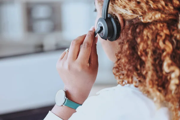 Talking, advice, discussion being had by a call center agent wearing a headset in an office at work. Customer service, support and conversation given to a client from a female working at a startup.