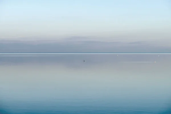 Calm, cool and relaxing front view of the ocean horizon, copy space on top. Mist over the sea on a new morning. Clear and blue sky during a tranquil dusk evening with natural background